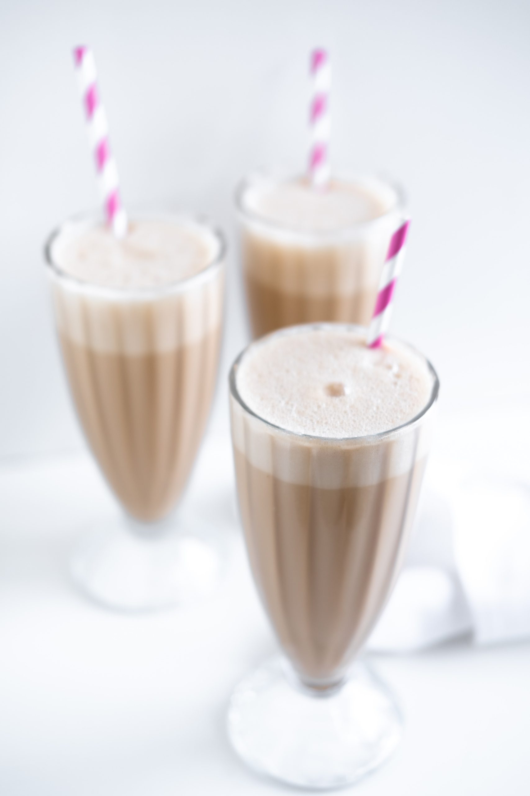 three chocolate protein shakes in tall glass